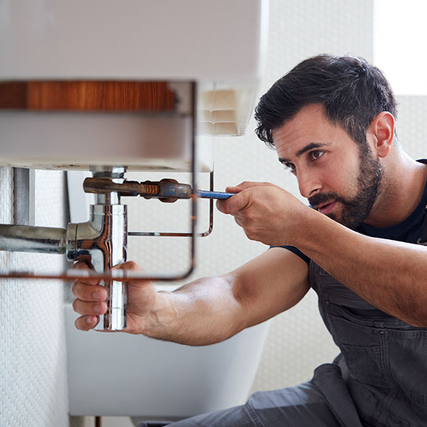 lose-up of a plumber working on a copper pipe installation using tools.