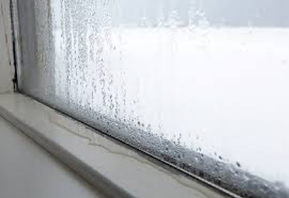 Water is visible pooling on a window frame at the bottom of a window with condensation