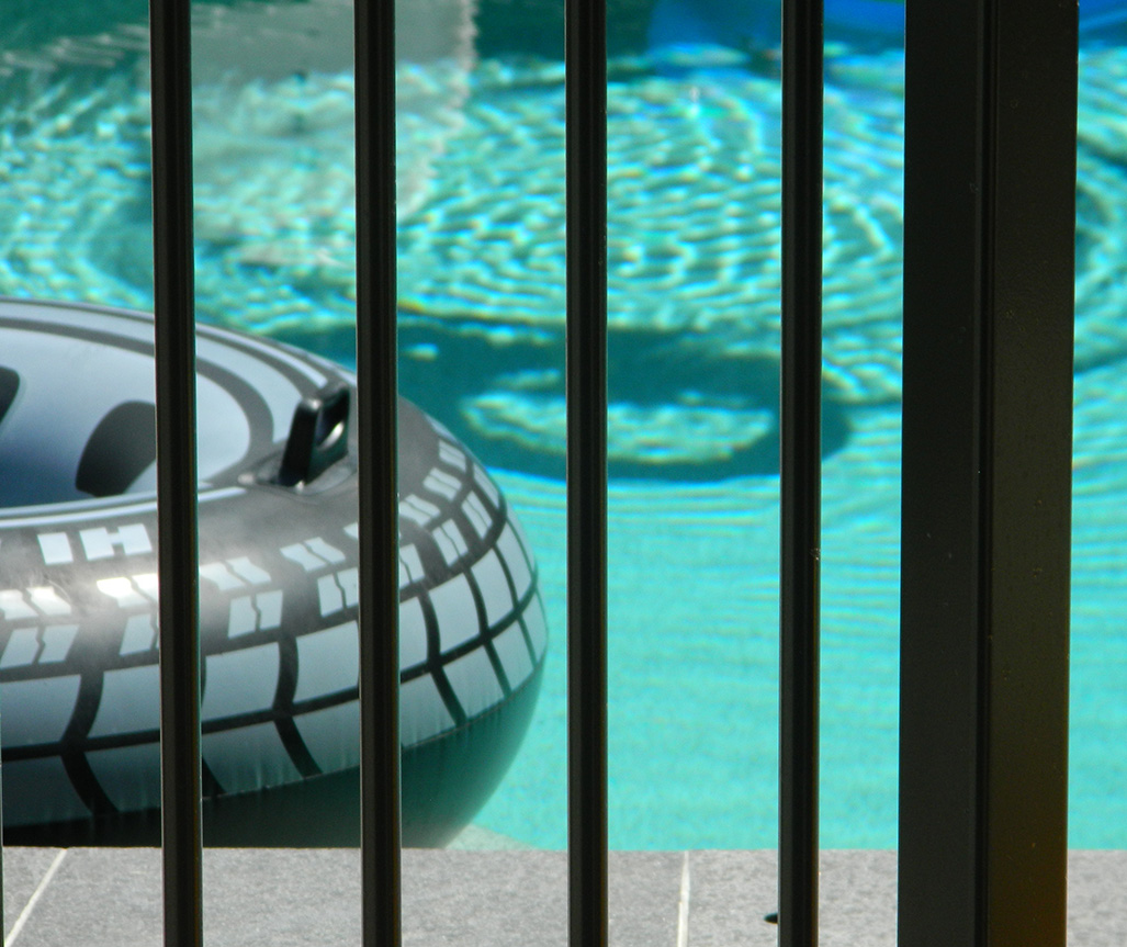 A pool behind a fence with a floating ring.