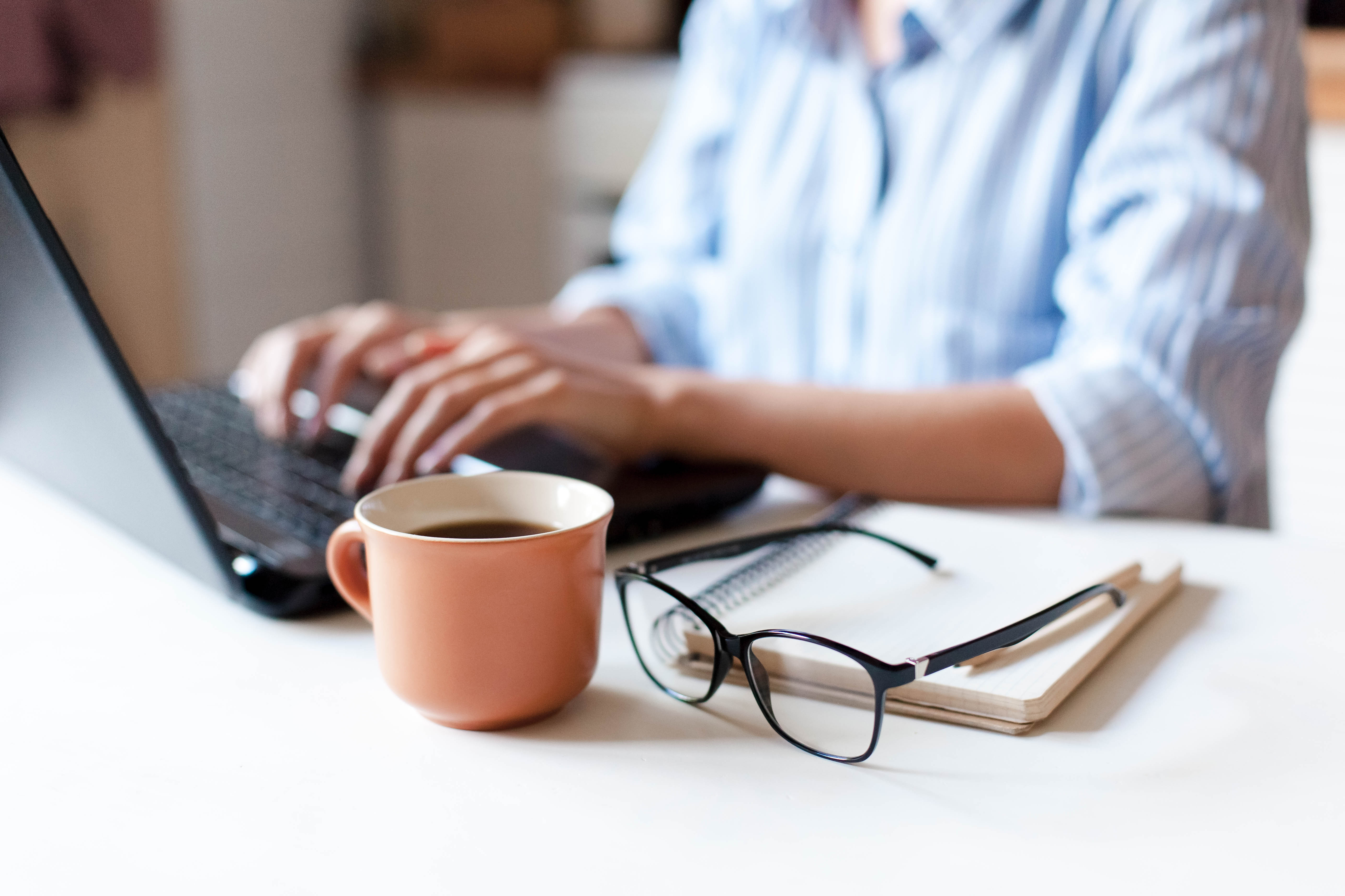 Typing on a coputer with a coffee nearby